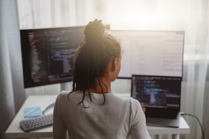 Woman at a computer with code, representing cloud security automation.